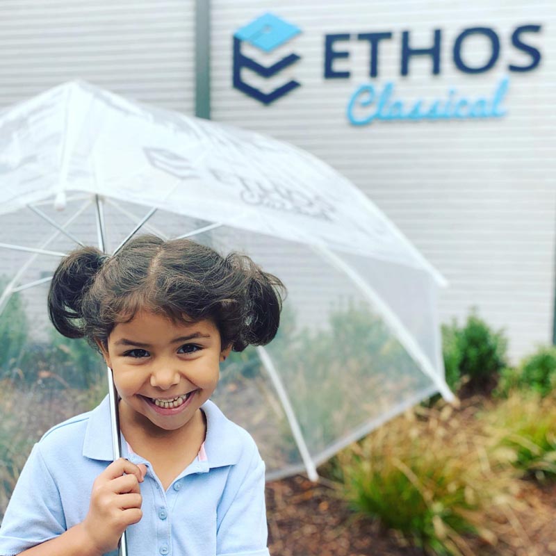Ethos student smiling while holding white transparent umbrella
