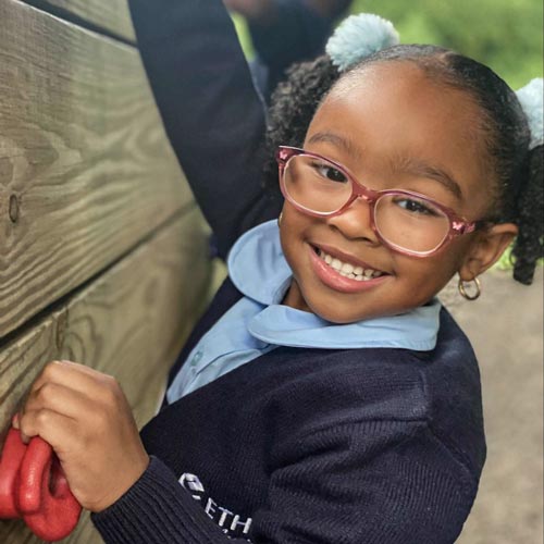 Black girl with eyeglasses climbing a wood